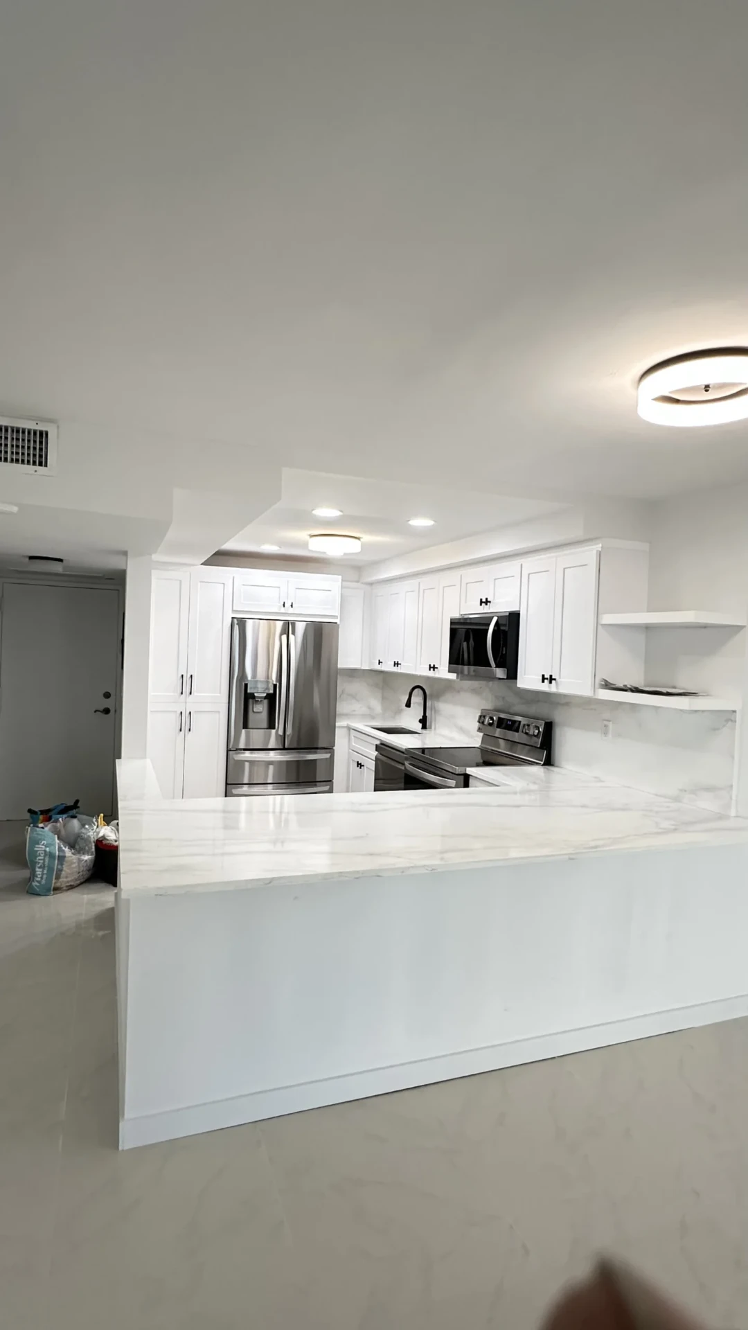 Remodeled kitchen with tall pantry cabinets and marble island