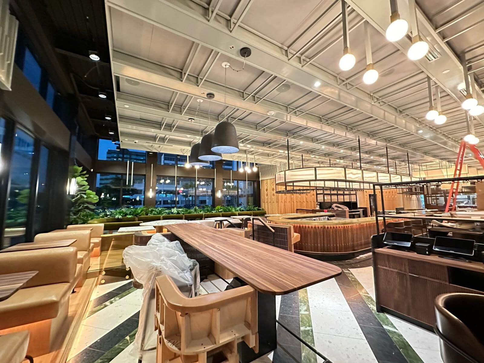 Restaurant dining room with banquettes, planters and pendant lighting