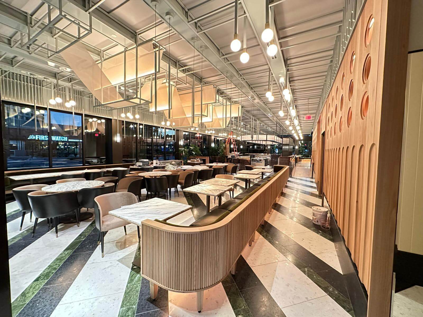 Dining row with fluted banquette, terrazzo floor and oak paneling