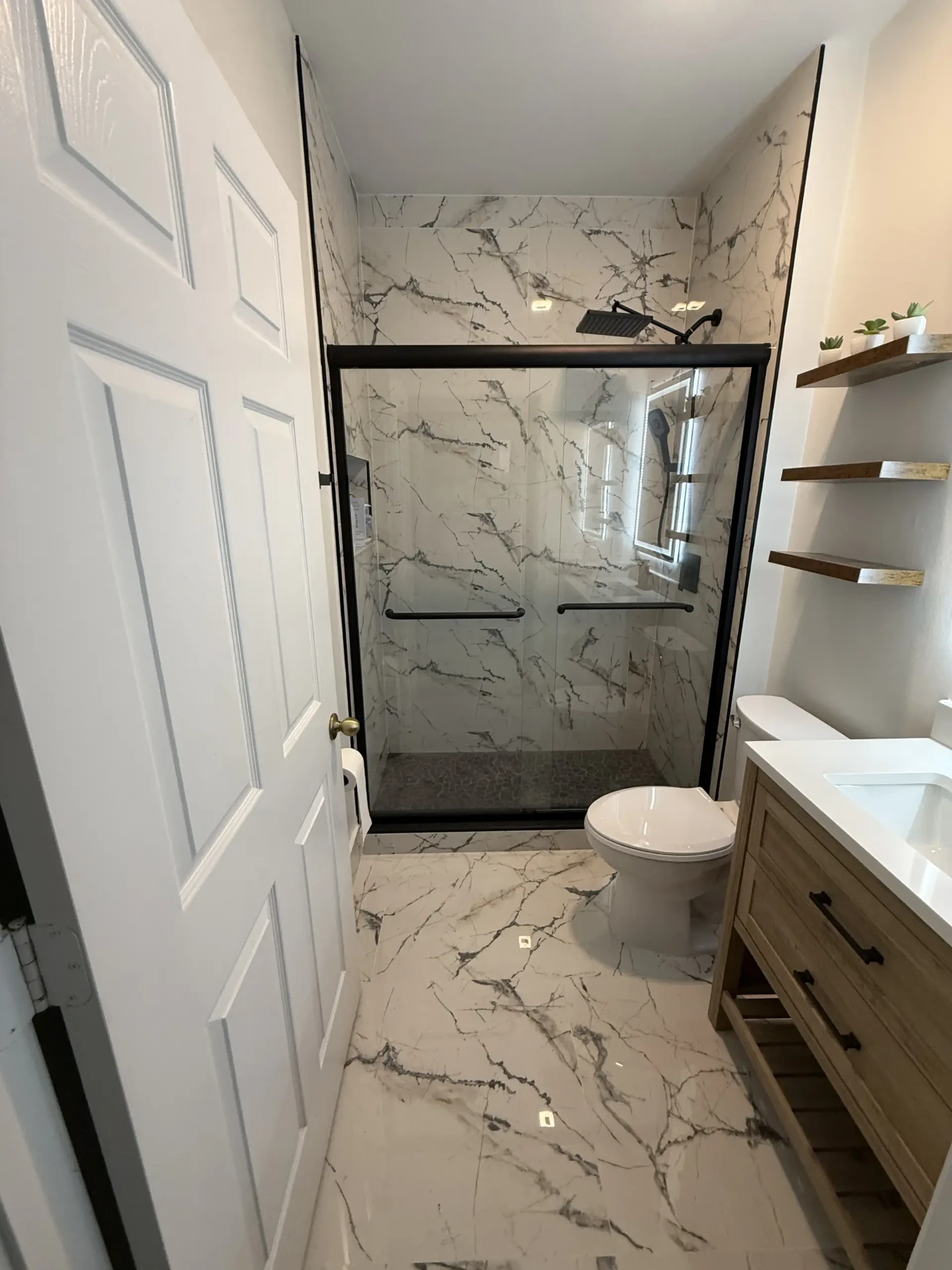 Finished bathroom with floating shelves, new vanity and porcelain floor