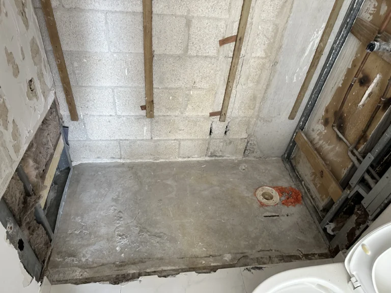 Prepared shower base and rough plumbing after demolition
