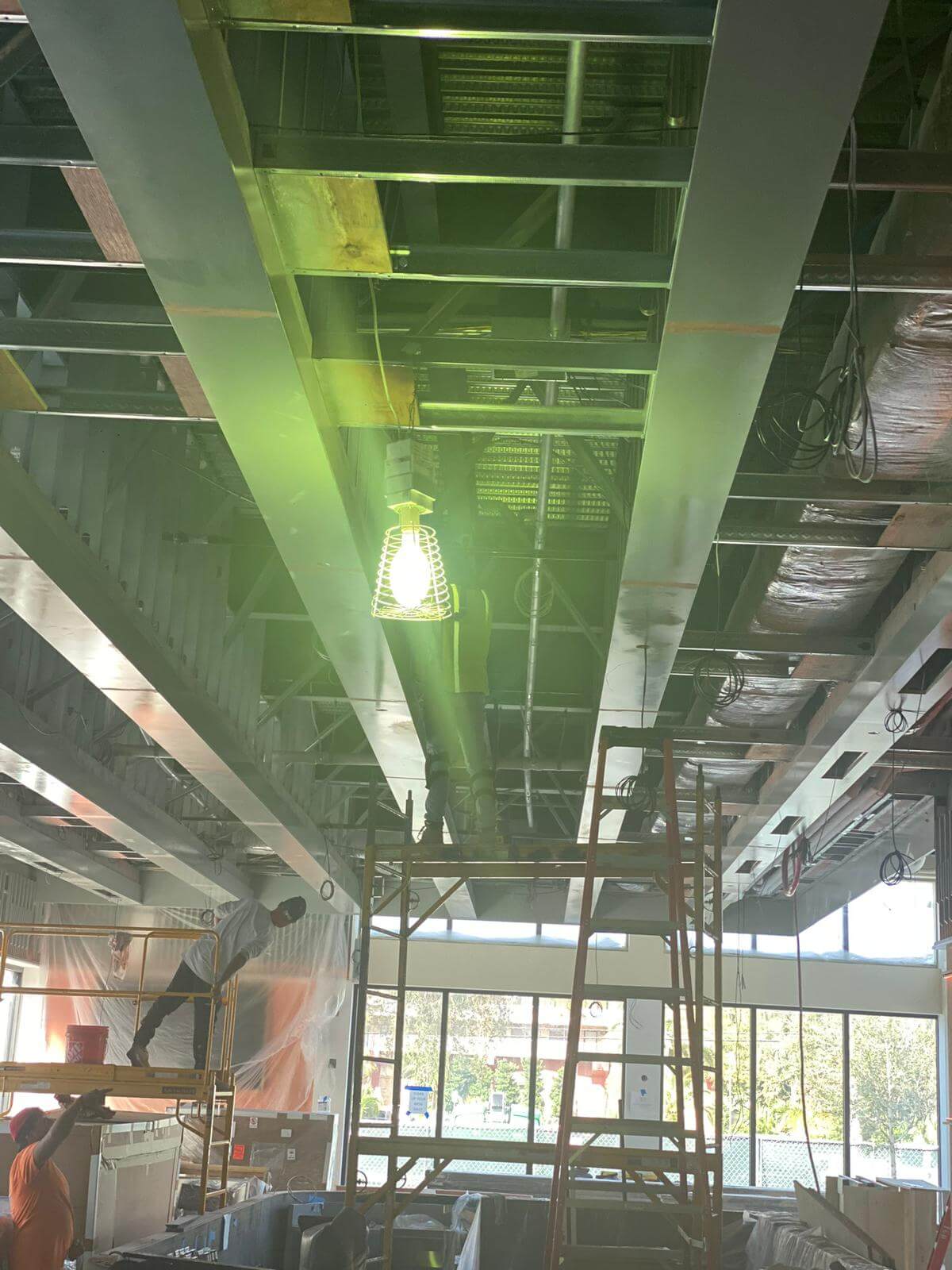 Painters working from scaffolding on a commercial ceiling